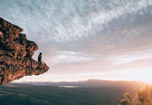 Work and Travel Reisende sitzt auf Felsen und blickt in die Ferne