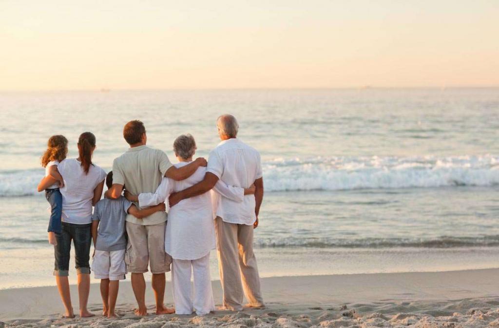 Drei Generationen einer australischen Familie stehen am Strand