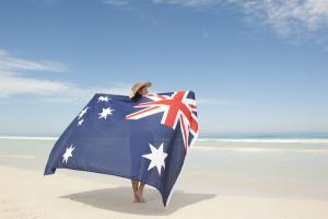 Frau steht mit australischer Flagge am Strand