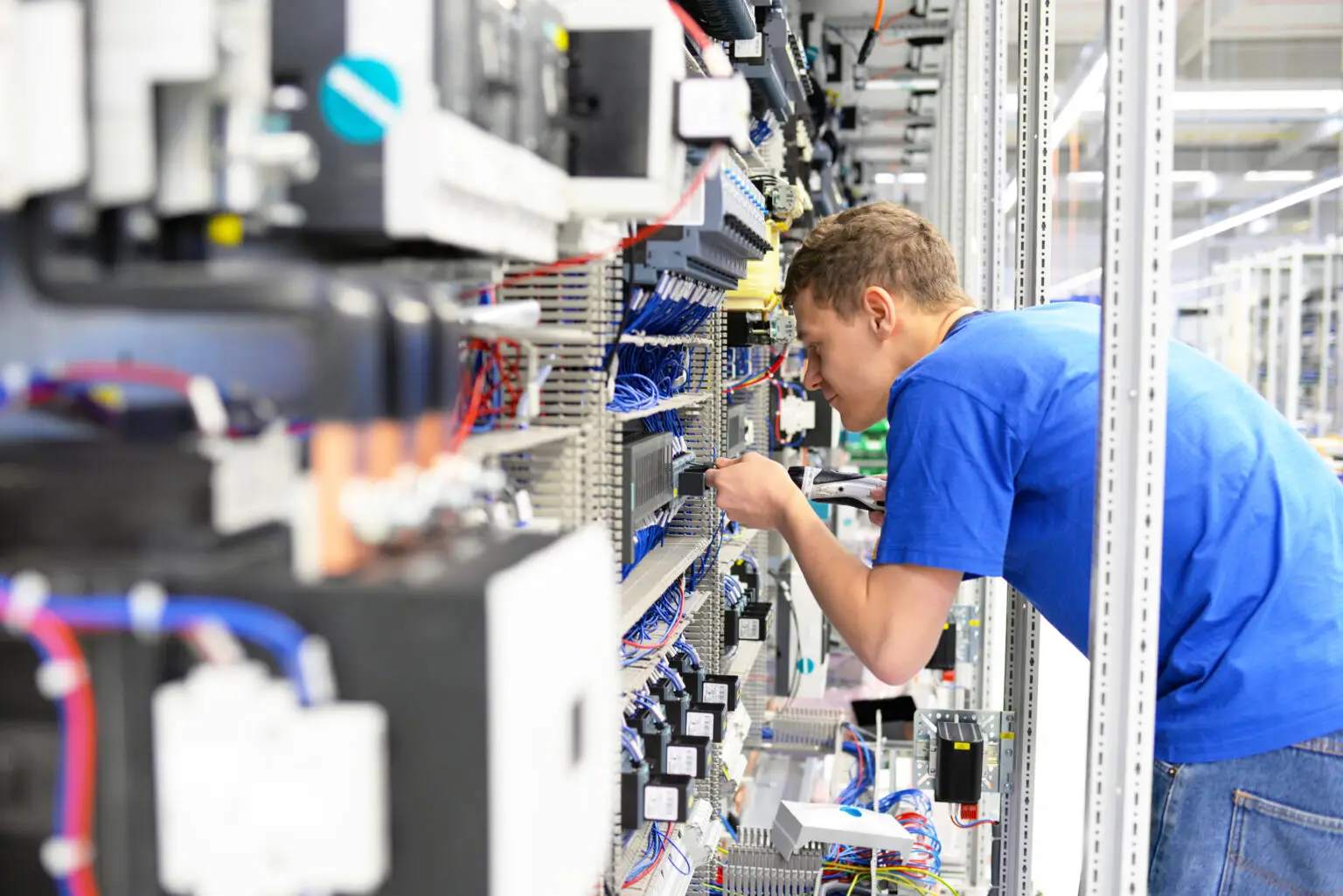 young apprentice assembles components and cables in a factory in a switch cabinet - workplace industry with future