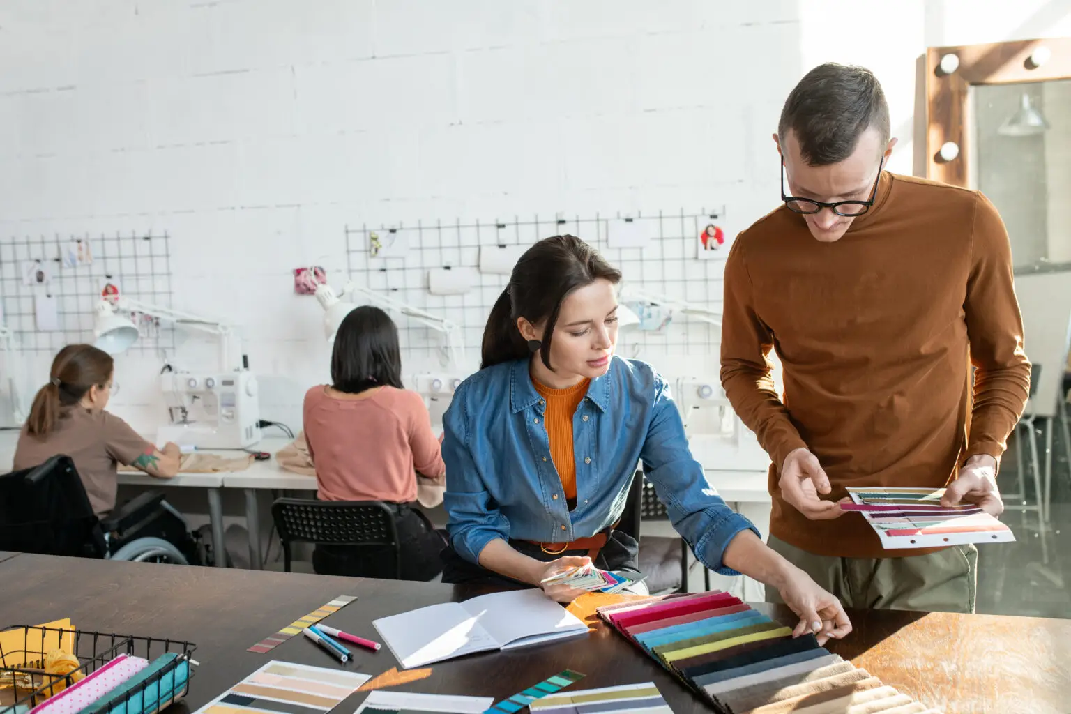 Two,Fashion,Designers,Working,Over,New,Collection,Against,Seamstresses