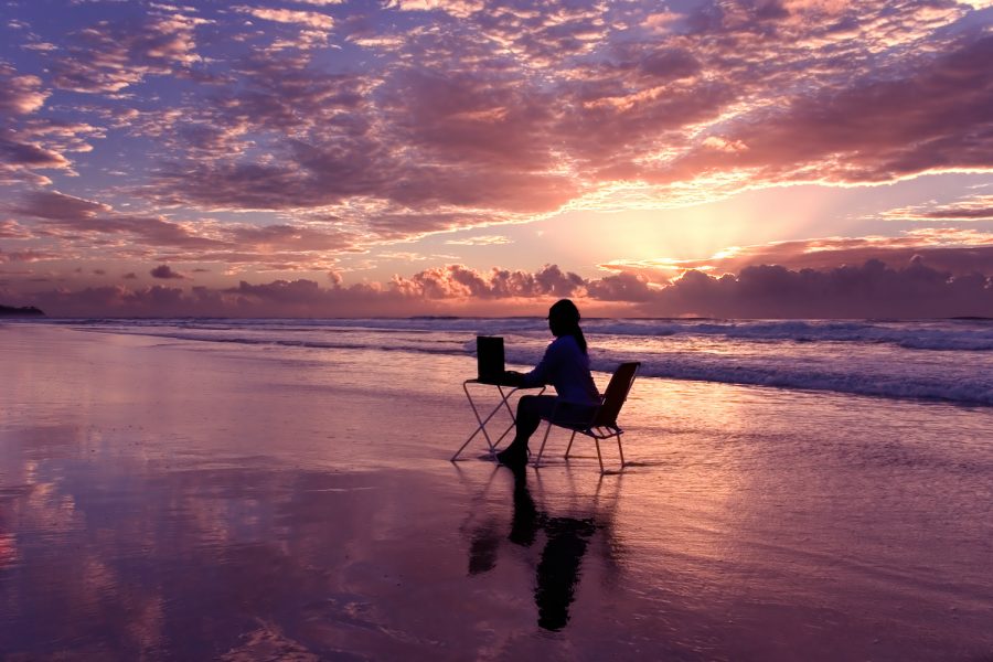 Woman with laptop working at sunrise